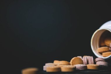 Bebek vitaminler ve Takviyeler yakın, karanlık bir arka planda beyaz şişeyle bağışıklık sağlamak. C vitamini, E vitamini, Vitamin D3 de dahil olmak üzere.