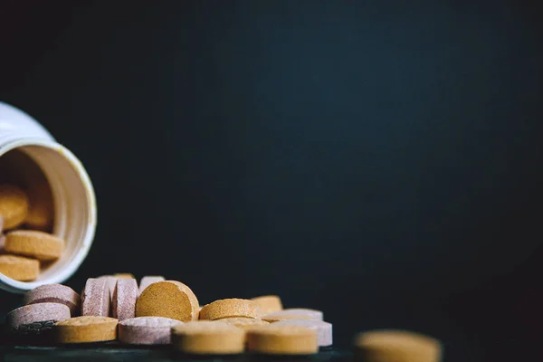 Close up of baby vitamins and supplements, maintain immunity on a dark background with a white bottle. Including vitamin C, Vitamin E, Vitamin D3.