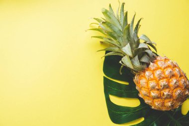 Olgun taze ananas ve renk arka plan, üstten görünüm üzerinde monstera ağacının yaprak