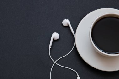 Kulaklıklar ve siyah arka planda bir fincan kahve. Müzik konsepti. Kopyalama alanı ile üstte görünüm