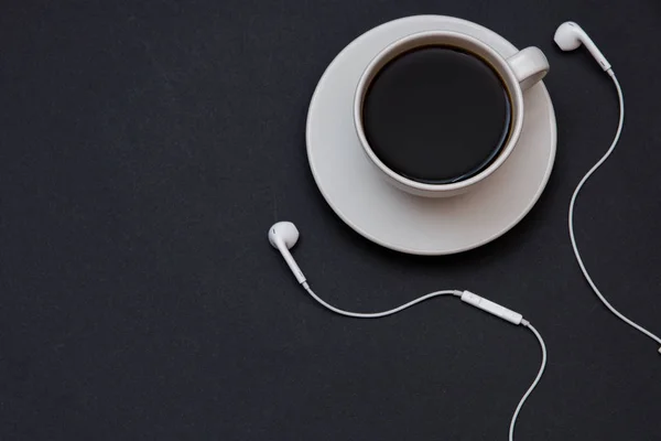 Headphones and a Cup of coffee on a black background. Musical concept. Top view with copy space — Stock Photo, Image