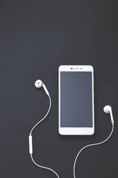 Siyah arka planda kulaklıklar ve mobil cihazlar. Müzik konsepti. Kopyalama alanı ile üstte görünüm