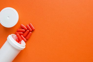 Portakal arka planda beyaz bir şişe turuncu kapsüller. metin, seçici odak, üst görünüm için boşaltmak. İlaç istismarı kavramının tedavisi için ağrı ilaçları, sağlık, haplar