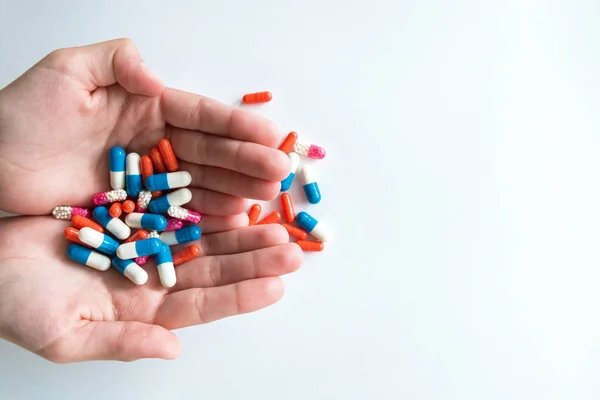 Multicolored capsules in hand isolated on white background, copyspace for text, selective focus, top view. Pain meds, health, pills for the treatment of the concept of drug abuse