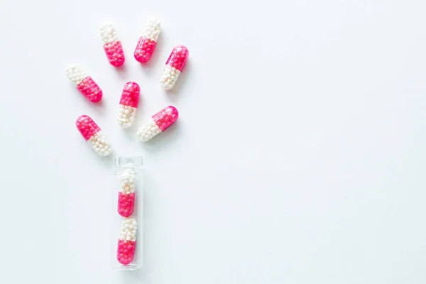 Cápsulas de garrafa rosa em fundo isolado branco, espaço de cópia para texto, foco seletivo, vista superior. Dor drogas, saúde, pílulas para o tratamento do conceito de dependência — Fotografia de Stock