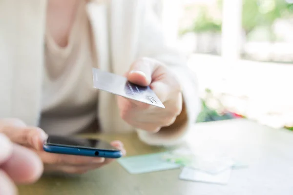 Beyaz ceketli bir kadın, internet üzerinden kredi kartıyla ödeme yapıyor, internet üzerinden sipariş veriyor. Başarılı kadın işadamı mobil bankacılık uygulamasını kullanarak işlem yapıyor. Seçici odaklama