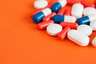 Turuncu arka planda izole edilmiş çok renkli kapsüller, metin için copyspace, seçici odaklama, üst görünüm. Ağrı ilaçları, sağlık, ilaç bağımlılığı kavramının tedavisi için haplar