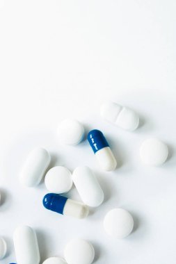 Beyaz arka planda yalıtılmış beyaz ve mavi kapsüller, metin için copyspace, seçici odaklama, üst görünüm. Ağrı ilaçları, sağlık, ilaç bağımlılığı kavramının tedavisi için haplar