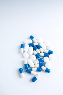 Beyaz arka planda yalıtılmış beyaz ve mavi kapsüller, metin için copyspace, seçici odaklama, üst görünüm. Ağrı ilaçları, sağlık, ilaç bağımlılığı kavramının tedavisi için haplar