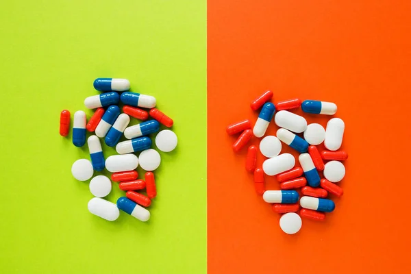 Multicolored capsules isolated two green and orange background, copyspace for text, selective focus, top view. Pain meds, health, pills for the treatment of the concept of drug abuse
