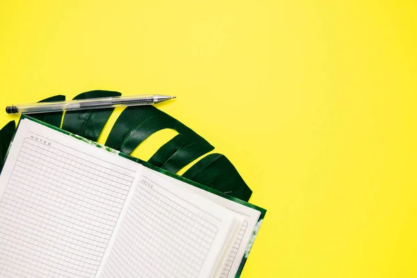 Bloc de notas blanco y pluma para escribir, hoja de monstera sobre fondo amarillo, espacio para copiar — Foto de Stock