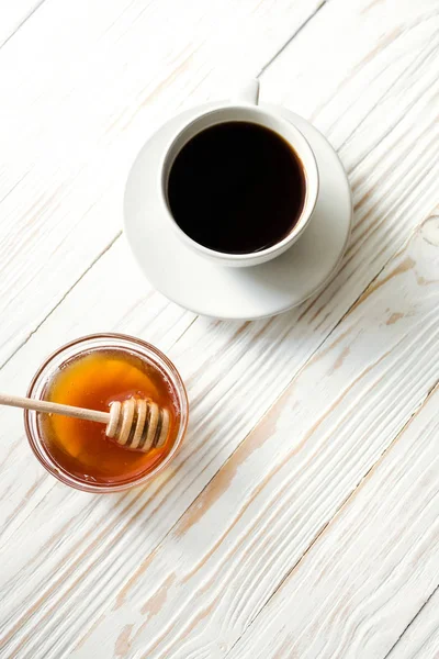 Una taza de café instantáneo y miel en un fondo de madera de textura blanca vista superior, acogedor y delicioso desayuno. Fondo rústico, imagen vertical — Foto de Stock