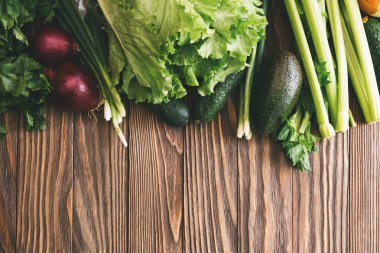 Taze organik yiyecekler, taze sebzeler. Marul, salatalık, kereviz, soğan, avokado ve maydanoz ahşap arka plan üzerinde kopya alanı ile