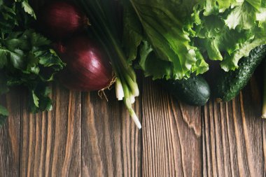 Taze organik yiyecekler, taze sebzeler. Marul, salatalık, kereviz, soğan, avokado ve maydanoz ahşap arka plan üzerinde kopya alanı ile