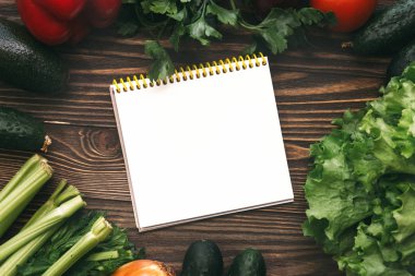 Taze organik yiyecekler, taze sebzeler. Marul, salatalık, kereviz, soğan, çan papper ve maydanoz kopya alanı ve not defteri ile ahşap arka plan üzerinde