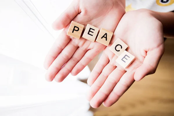 the word Peace is written in cubic letters in hands, selective focus