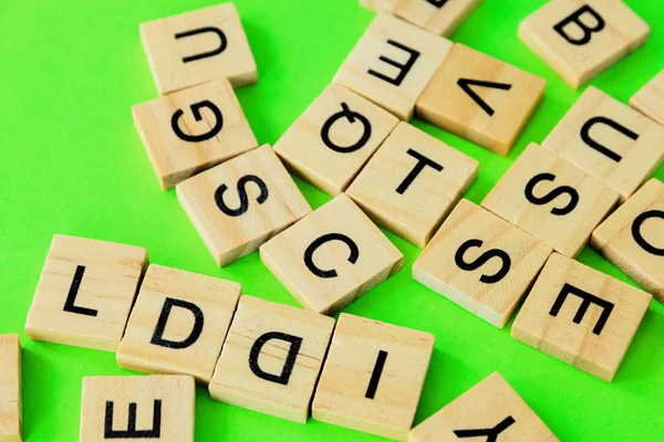 Pile of wooden letters on the surface of a green background, selective focus — Stock Photo, Image