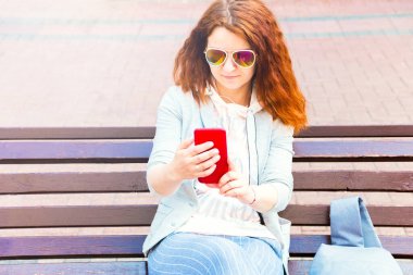 Güzel, neşeli, genç, kızıl saçlı bir kadın güzel bir günde parkta güzel vakit geçiriyor ve selfie çekiyor..