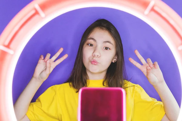A girl blogger talks to subscribers, conducts a live broadcast, looks at the smartphone screen. Make a video call to friends and parents. Social networks, instagram, selfies.