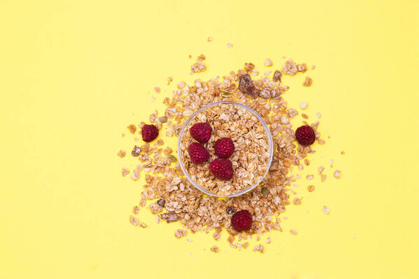 Crispy muesli with raspberry dry Breakfast isolated on yellow background selective focus, top view.