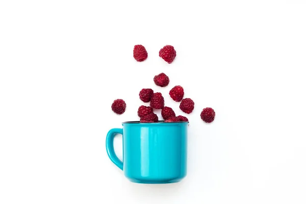 Juicy raspberry in blue mug isolated on white background selective focus top view.