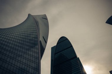Moskova şehir bölgesinin yüksek modern cam kulesi bulutlu karanlık gökyüzüne ve batan güneşe karşı bir iş arka planı için. Moskova, Rusya, Haziran 2020.
