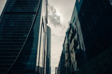 Moskova şehir bölgesinin yüksek modern cam kulesi bulutlu karanlık gökyüzüne ve batan güneşe karşı bir iş arka planı için. Moskova, Rusya, Haziran 2020.