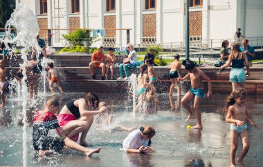 Sıcak yaz havası, parktaki çeşmede yıkanan bilinmeyen küçük çocuklar. Moskova, Rusya, Temmuz 2020.