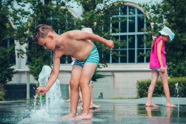 Sıcak yaz havası, parktaki çeşmede yıkanan bilinmeyen küçük çocuklar. Moskova, Rusya, Temmuz 2020.