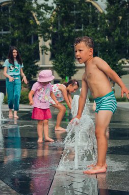 Sıcak yaz havası, parktaki çeşmede yıkanan bilinmeyen küçük çocuklar. Moskova, Rusya, Temmuz 2020.