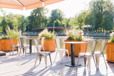 Sıcak bir yaz gününde, şehir parkındaki göletin yanındaki açık havada bir yazlık kafe.