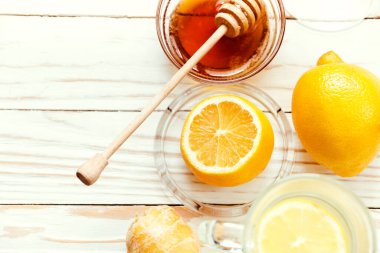 Beyaz ahşap arka planda zencefil-limon ve bal ile sıcak çay iç, soğuk algınlığını önle. Seçici odak.