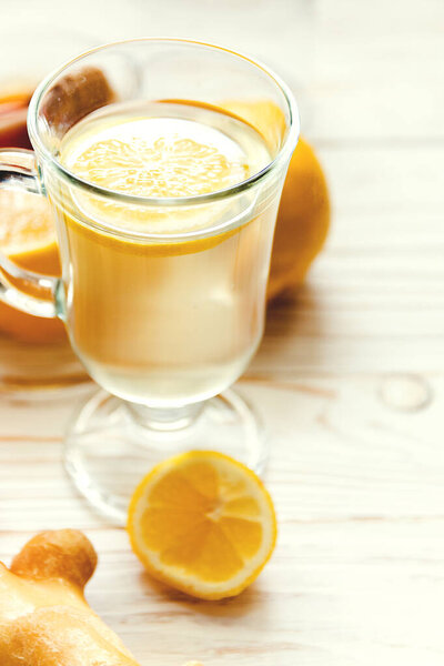 Drink hot tea with ginger-lemon and honey on white wooden background, prevention of colds. Selective focus.