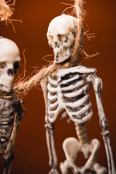 Két Hamis Csontváz Egy Kötélen Háttérben Narancssárga Alapon Halloween Dekoráció — Stock Fotó