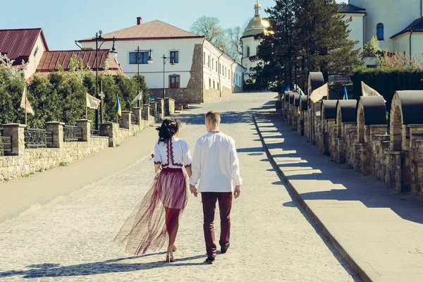 Krásná mladá dvojice chodí do kostela v výšivky na svatbě — Stock fotografie