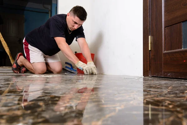 Чоловік розміщує керамічну плитку для підлоги в положенні над клеєм — стокове фото