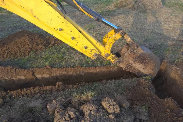 A work excavator digs a trench in a country house