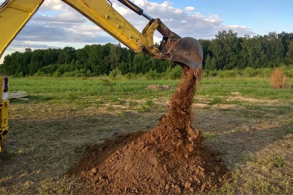 Un escavatore di lavoro scava una trincea per la fondazione di un edificio — Foto Stock