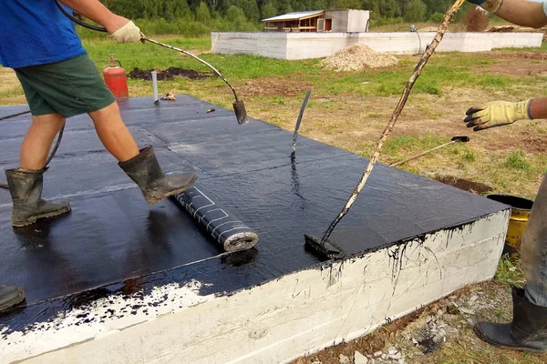 Instalación profesional de impermeabilización sobre cimientos de hormigón Dos trabajadores en obra . — Foto de Stock