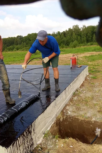 Instalación profesional de impermeabilización sobre cimientos de hormigón Dos trabajadores en obra . — Foto de Stock