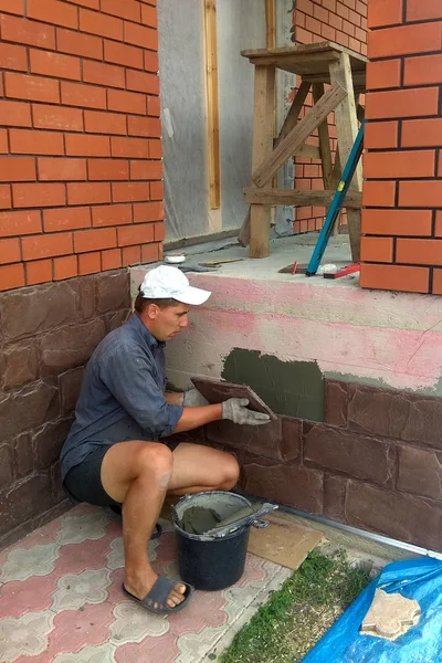 gluing a granite stone on the foundation of the building facing 2018