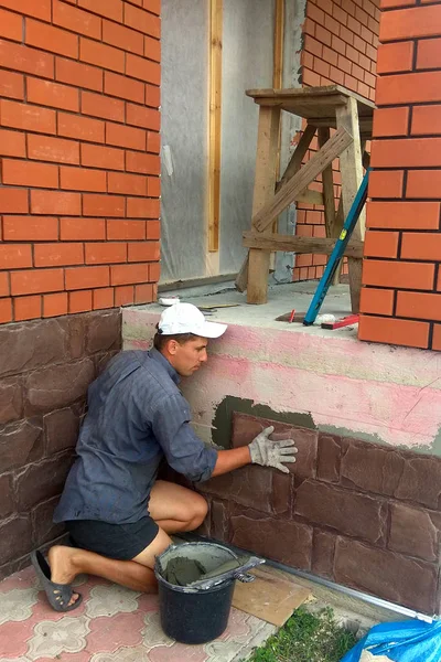 gluing a granite stone on the foundation of the building facing 2018