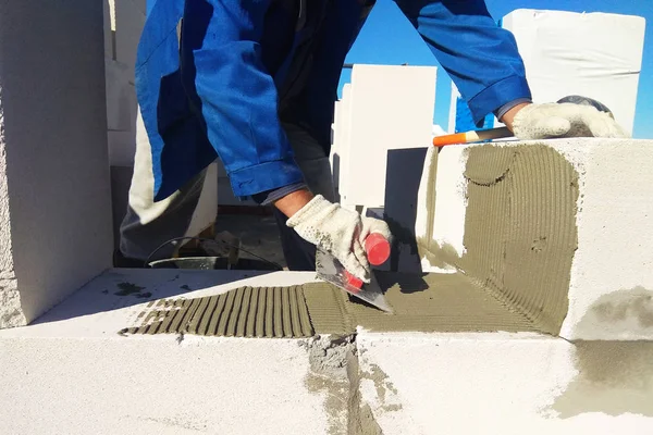 The master monitors the wall with gas blocks using glue and trowel 2018