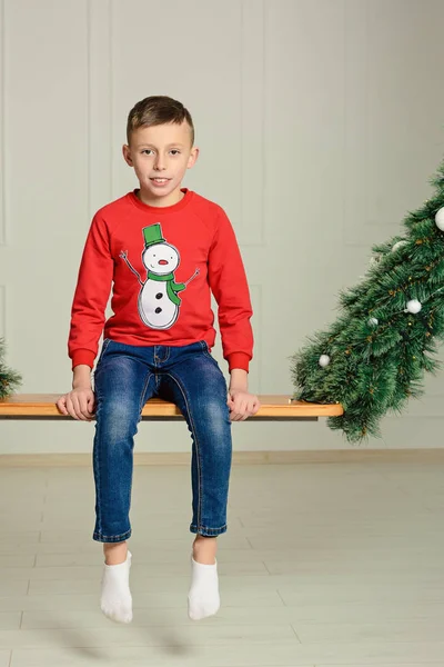 Junge Sitzt Auf Einer Schaukel Pullover Mit Einem Schneemann Auf — Stockfoto