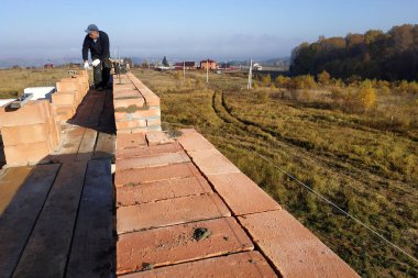 bir işçinin bir inşaat alanı üzerinde bir tuğla koyar gökyüzüne ve bu alan 2018