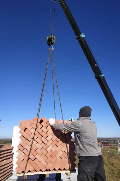 The car crane transfers the brick to the construction site on the background of the sky and field 2018