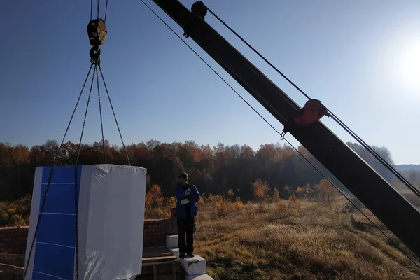 the worker helps the car crane driver to unload the blocks by showing the signs with their hands 2018