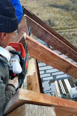İşçiler kirişleri 2019 chainsaw evin çatısına kesti.