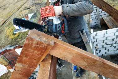 İşçiler kirişleri 2019 chainsaw evin çatısına kesti.