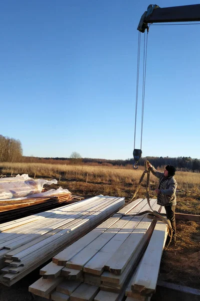 Unloading boards from the side of the crane with the help of people 2019